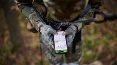Hunter used HuntWise on phone while in tree saddle, how to use a hunting app concept.
