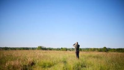 Hunter using binoculars in a field, how to find property lines in Wyoming concept. 