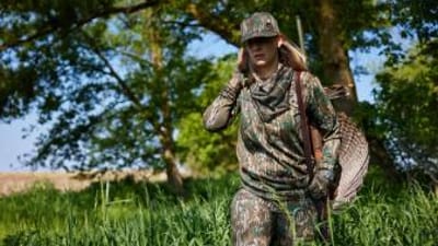 A female hunter carries a turkey after a hunt, hunting Wisconsin Turkey Zones concept.
