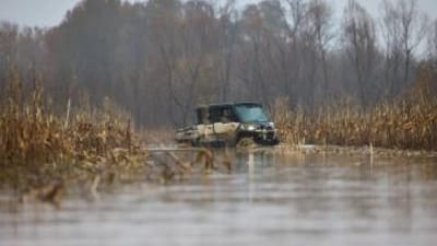 Hunters in an ATV in a duck habitat, building a duck pond concept.