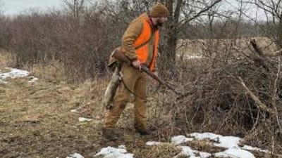 Hunter with rabbit on belt hunting in the woods, where to find rabbits concept.