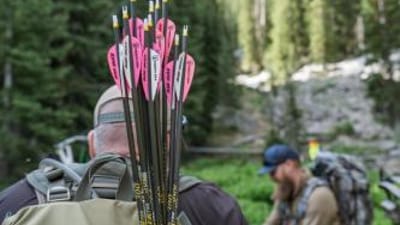 Hunters with arrows and a compound bow in the woods.