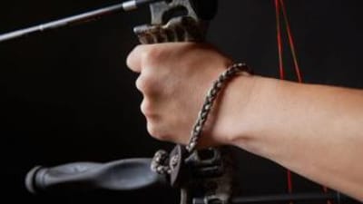 Close-up of a wrist bow sling on a wrist while holding a bow.