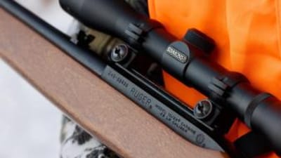 Close-up of hunter's orange vest and small game rifle, rabbit hunting gear list concept.