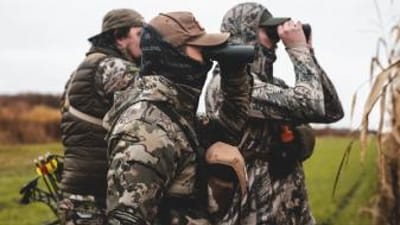Hunters scouting using binoculars, understanding whitetail facts concept.