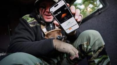 John Dudley holds up a phone showing the HuntWise hunting app RutCast feature.
