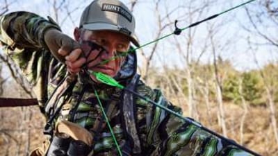 John Dudley wears a HuntWise hat and draws an arrow, how to get better at archery concept.