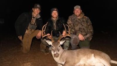 Three hunters smile with a deer after a successful hunt, meat for holiday venison recipes concept.