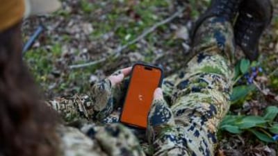 Hand holds phone showing HuntWise on screen, HuntWise vs onX concept. 