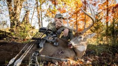 Hunter with buck deer and bow after hunt, represents post season bow maintenance.
