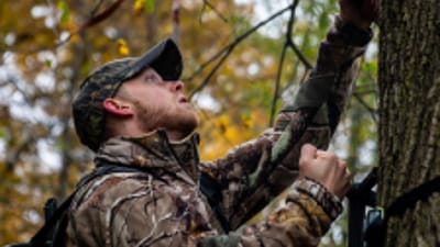 A deer hunter setting up a tree stand.
