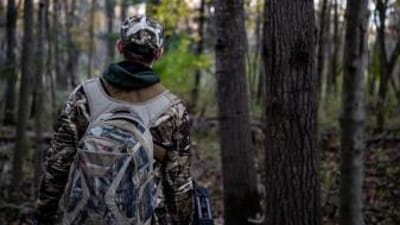 A hunter in the woods with essential hunting gear.