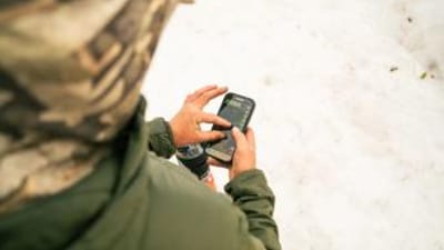 Hunter using phone with HuntWise on screen, how to find mule deer concept.