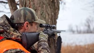 A hunter aims a rifle, choosing the right gun calibers concept.