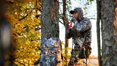 Hunter in tree using deer call, best deer calls for pre-rut concept.