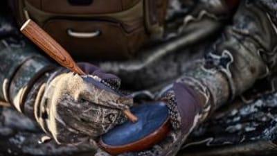 A hunter with camera equipment using HuntWise in the field, hunting influencer concept.