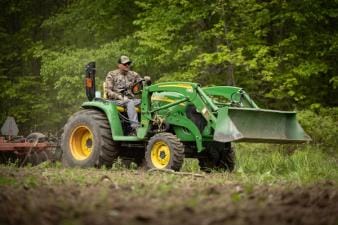 A hunter uses a tractor to clear land, when to plan spring food plots for deer concept.
