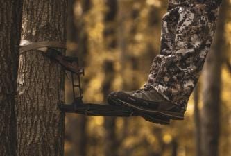 Close-up of a hunter's feet on a saddle hunting platform in a tree.