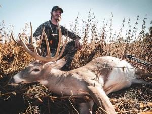 A hunter with a deer after a kill shot, hunting whitetail deer concept.