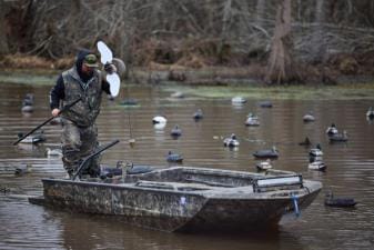 Hunter in boat sets out decoys, duck decoy hunting concept.