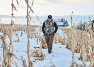 Jeff Sturgis walks through a snowy field, understand weather and deer movement concept.