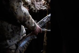 Hunter with shotgun in duck blind, waterfowl shotguns concept.