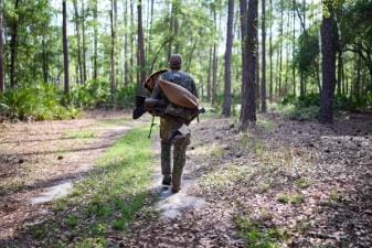 A hunter carries turkey hunting gear in the woods, how to hunt turkey in the spring concept.