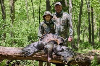 A dad and son in camo after a turkey hunt, hunting gifts for dad concept.
