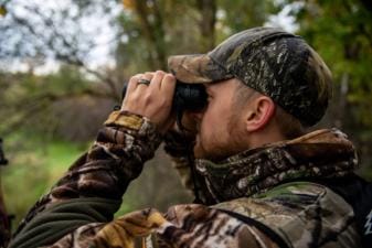 A hunter using binoculars, how to scout for deer land.
