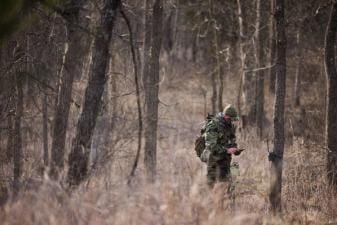 Hunter John Dudley checks phone and trail cam in woods, look for deer hunting land concept.