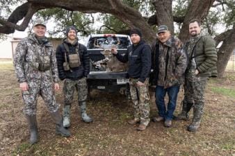 Several hunters gather around a buck in the back of a truck after a hunt.