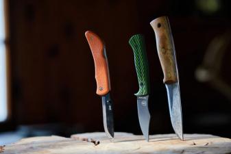 Three hunting knives stuck into a wood stump, choosing hunting knives concept.