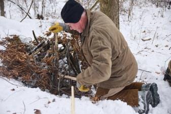 Man sets trap in the snow, PA trapping season concept.