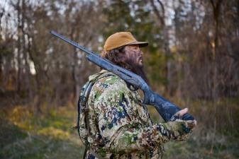 Side view of hunter with shotgun on shoulder, shotgun for hunting concept.