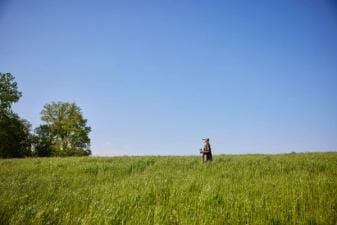 A woman in a green field, looking for private hunting land near me concept.