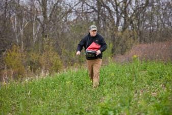 Jeff Sturgis with a seed spreader walks through a food plot, what do deer eat concept.