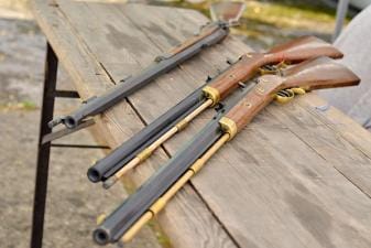 Three muzzleloader rifles on a table.