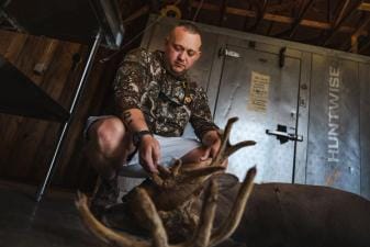 Hunter with buck deer after hunt in front of cooler, hunting whitetail before the rut concept.