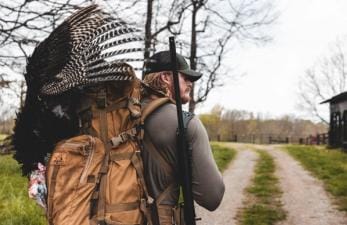 A hunter with a harvested turkey after a successful turkey hunt.