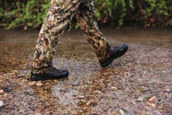Close-up of a hunter's boots as he walks through water, summer huntingn boots concept.