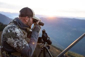Hunter glassing on hill, high country mule deer hunting concept.
