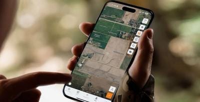 Hand holding phone showing land lines in HuntWise app, hunting maps with property lines concept.