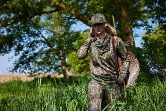 A female hunter carries a turkey after a hunt, hunting Wisconsin Turkey Zones concept.