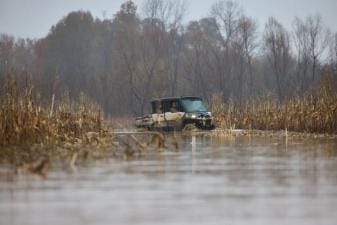 Hunters in an ATV in a duck habitat, building a duck pond concept.