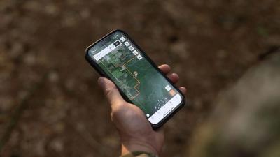 Close-up of hand holding phone showing HuntWise map, hunting app with property line concept.