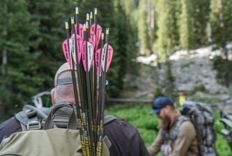Hunters with arrows and a compound bow in the woods.