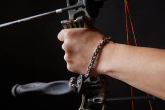 Close-up of a wrist bow sling on a wrist while holding a bow.