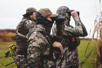 Hunters scouting using binoculars, understanding whitetail facts concept.
