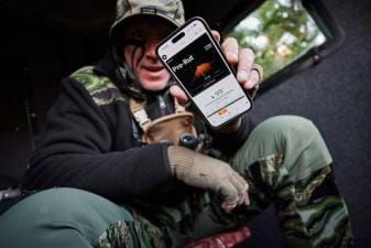 John Dudley holds up a phone showing the HuntWise hunting app RutCast feature.