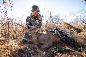 A female hunter shows off a deer after a hunt, women's hunting gifts concept.